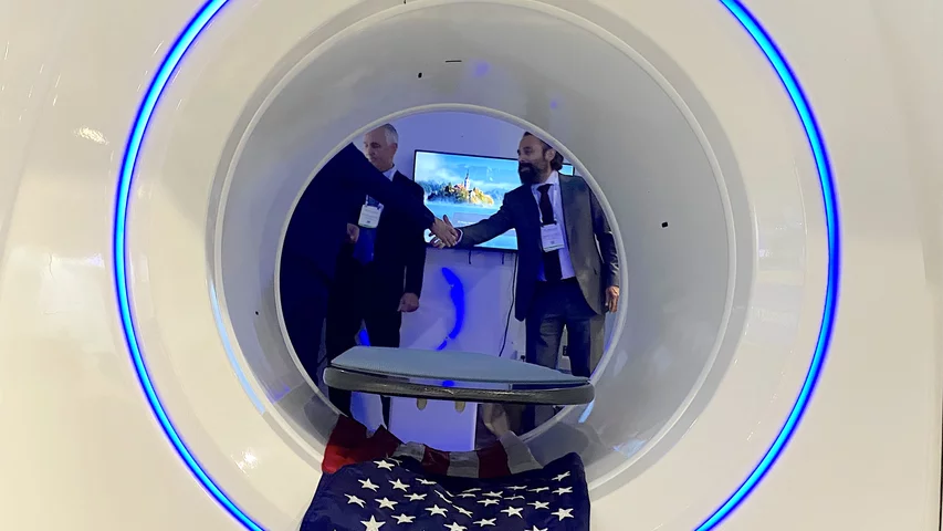A handshake during a meeting inside a trailer designed for disasters or military use with a mobile iCRco Claris XT CT system. Photo by Dave Fornell. #RSNA #RSNA23 #RSNA2023