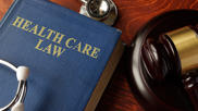 A book titled "Health Care Law" next to a gavel and a stethoscope 