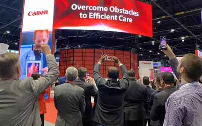 A crowd of attendees capturing video of Canon's unveiling of two new AI-enabled CT systems at during RSNA 2023. Photo by Dave Fornell. #RSNA #RSNA23 #RSNA2023
