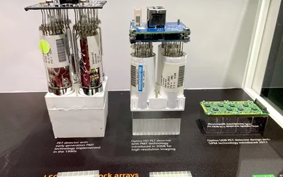 Display at Siemens showing the evolution from PET photo-multiplier tube detectors to much more compact and efficient digital detector technology between the 1990s to the latest system displayed at RSNA 2023. The small electronic board on the right is Siemen's current SiPM technology.Photo by Dave Fornell. #RSNA #RSNA23 #RSNA2023